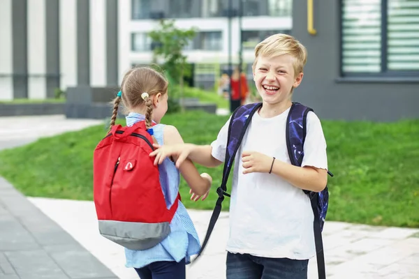 友達と会う 学校に戻る バックパックを持った2人の子供が学校の近くで会った 子供時代の概念 — ストック写真