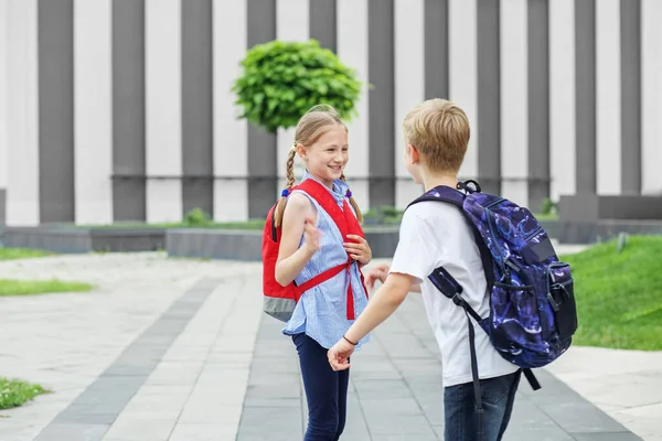 和朋友见面回学校去两个背着背包的孩子在学校附近相遇了 友谊和童年的概念 — 图库照片