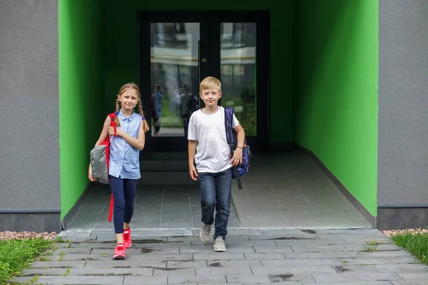 Двоє Дітей Виходять Шкільних Дверей Студенти Мають Шкільні Рюкзаки Ними — стокове фото