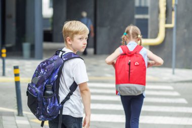 Traffic road rules. Child safety. School time. Back to school. Little pedestrians with backpacks walk to school and cross road at crosswalk.