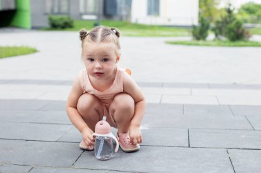 Su içen küçük bir kız. İki yaşında. Sızdırmaz şişe.
