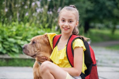 Köpekle gezen çocuk. Okuldan sonra okuldaki kız dışarıda eğleniyor. Evcil hayvan, arkadaşlık ve çocukluk kavramı.