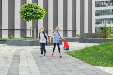 Sırt çantalı kız ve erkek. Okula dönelim. Çocuklar okumak için okula koşar. Okul derslerinin başlangıcı..