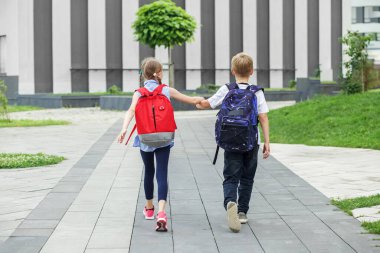 Sırt çantalı kız ve erkek. Okula dönelim. Çocuklar okumak için okula giderler. Okul derslerine başlıyorum. Okul, eğitim, eğitim, arkadaşlık, çocukluk kavramı