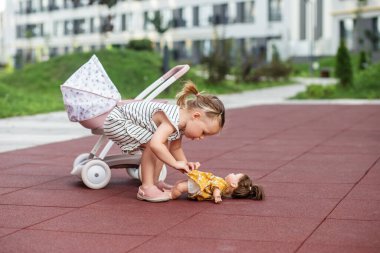 Bebek arabasında oyuncak bebeği olan küçük bir kız. İki yaşında. Gelişim aşamaları. İlk yıllar