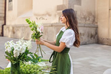 Başlangıçta başarılı küçük işletme girişimcisi kadın çiçeklerle duruyor ve buket yapıyor..