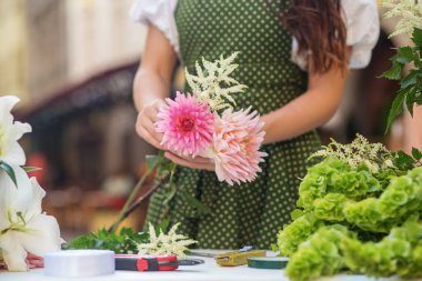 Çiçekçi iş başında. Farklı çiçeklerden güzel buket yapan bir kadın. İş yeri. Küçük bir iş. Kapat.
