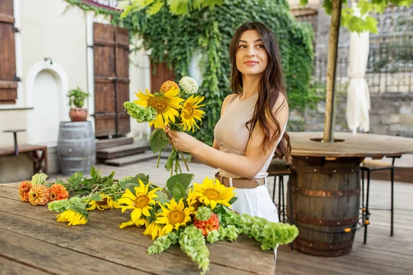 stock image Startup successful small business entrepreneur owner woman standing with flowers and makes bouquet.