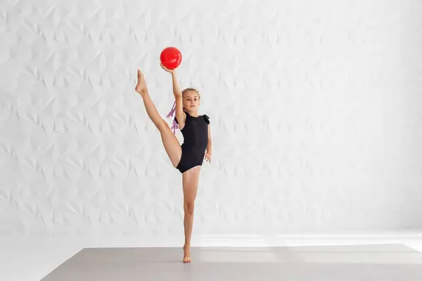 Rhythmic gymnastics. Preteen girl athlete rhythmic gymnastic in black suit does exercise with ball. Children\'s professional sports. Copy space