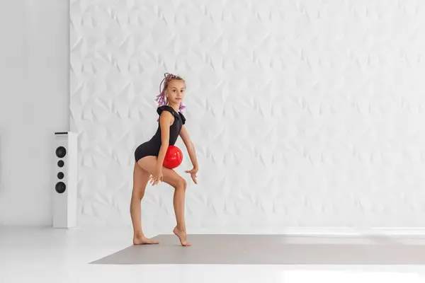 Rhythmic gymnastics. Preteen girl athlete rhythmic gymnastic in black suit does exercise with ball. Children's professional sports. Copy space