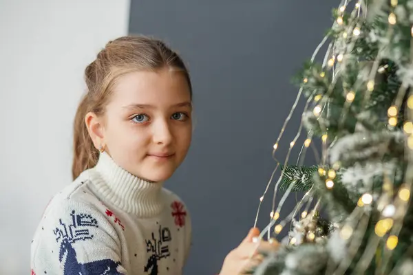Merry Christmas and Happy Holidays! Child preteen girl is decorating Christmas tree indoors. Concept New Year, Merry Christmas, holiday, vacation, winter, childhood.