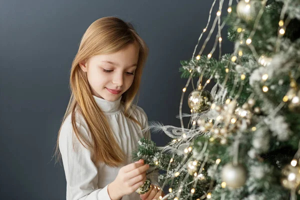 Merry Christmas and Happy Holidays. Child preteen girl is decorating Christmas tree indoors. Concept New Year, Merry Christmas, holiday, vacation, winter, childhood.