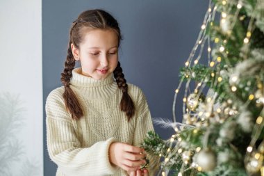 Mutlu Noeller ve mutlu tatiller. Çocuk reşit olmayan kız içeride Noel ağacı süslüyor. Kavram Yeni Yıl, Mutlu Noeller, tatil, kış, çocukluk.