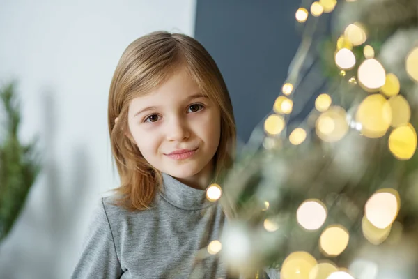 Merry Christmas and Happy Holidays. Child preteen girl is decorating Christmas tree indoors. Concept New Year, Merry Christmas, holiday, vacation, winter, childhood.