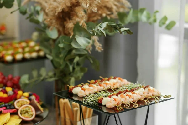 Food at event. Disposable plastic cups with snacks - shrimp with mozzarella cheese. Catering buffet table with snacks and appetizers.