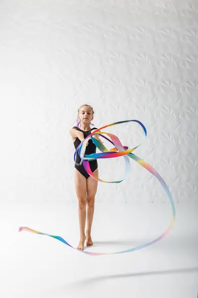 Rhythmic gymnastics. Preteen girl athlete rhythmic gymnastic in black suit does exercise with art ribbon. Children\'s professional sports. Copy space