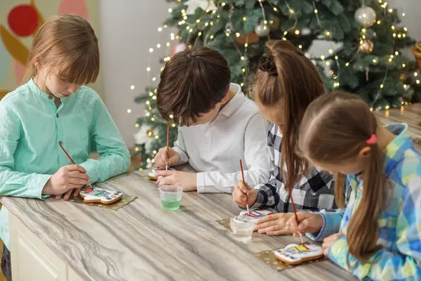 Group children draws food paints on Christmas homemade gingerbread cookies. Christmas concept.