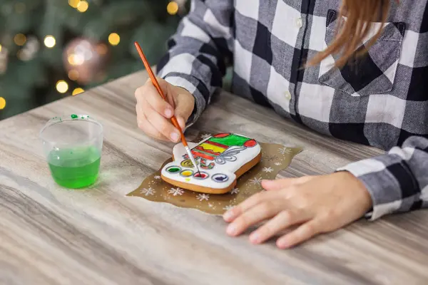 Child draws food paints on Christmas homemade gingerbread cookies. Christmas concept. Close up