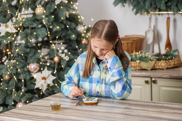 Preteen child draws food paints on Christmas homemade gingerbread cookies. Christmas concept