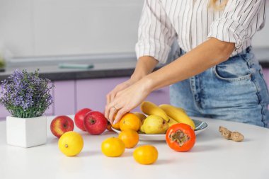 Organik yiyecekler. Kadın mutfakta tabağa meyve koyar. Diyet ve sağlıklı beslenme konsepti. Geçmişi. Kapat..