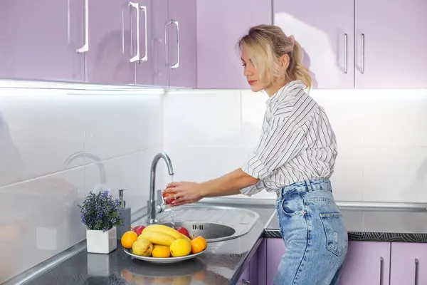 Woman washing fresh fruits in kitchen sink. Housework, cooking concept. Organic food.