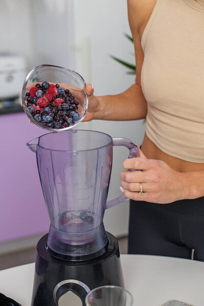 Healthy food concept. Close up of woman prepare to blending berries to make smoothie at home kitchen