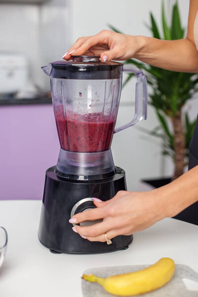 Healthy food concept. Close up of woman prepare to blending berries to make smoothie at home kitchen
