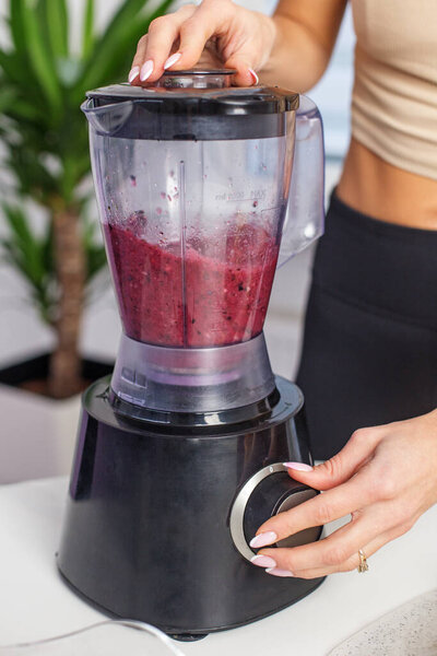 Healthy food concept. Close up of woman prepare to blending berries to make smoothie at home kitchen