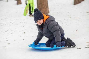 Çocuk kar tabaklarına biniyor. Açık hava oyunu. Soğuk hava. Kış zamanı