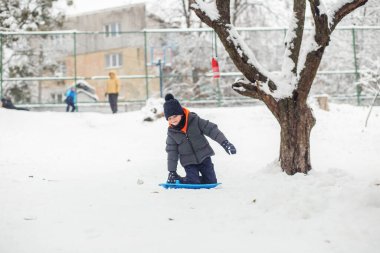Çocuk kar tabaklarına biniyor. Açık hava oyunu. Soğuk hava. Kış zamanı