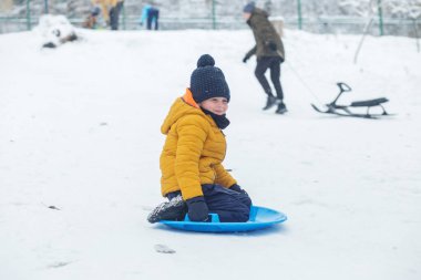 Çocuk kar tabaklarına biniyor. Açık hava oyunu. Soğuk hava. Kış zamanı