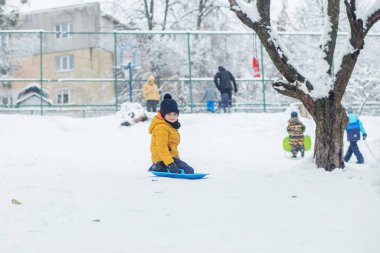 Çocuk kar tabaklarına biniyor. Açık hava oyunu. Soğuk hava. Kış zamanı