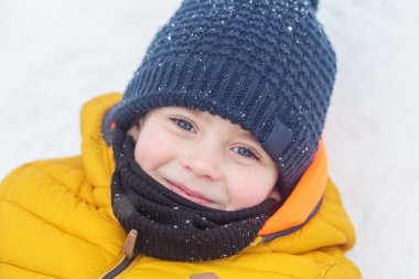 Kış oyunları açık havada. Kışın çocuklarla açık hava eğlencesi. Çocuk kış vakti, sıcak giysiler içinde yürüyor ve oynuyor.