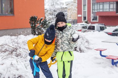 İki çocuk plastik oyuncakçıyla kartopu yaparken eğleniyor. Çocuklar kartopu oynuyor. Kış oyunları açık havada.