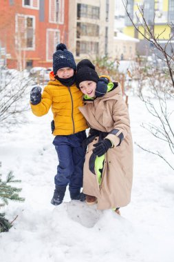 Kışın çocuklarla açık hava eğlencesi. Çocuklar kış vakti, sıcak kıyafetler içinde yürürler ve oynarlar.