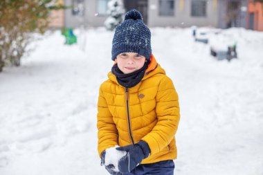 Kartopu savaşı. Kışın çocuklarla açık hava eğlencesi. Küçük çocuk eğleniyor ve kartopu oynuyor.