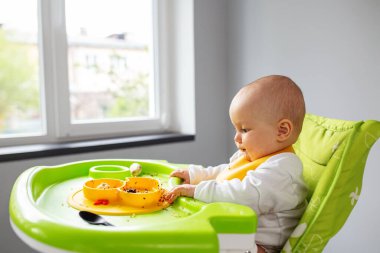 Bebeğin ilk beslenmesi bebek sandalyesinde tek başına yemek yemek ve ortalığı dağıtmak..