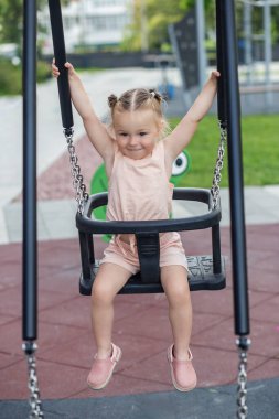 Gülücük saçı rüzgarda dalgalanan at kuyruklarıyla salıncakta güneşli bir günün tadını çıkarır..