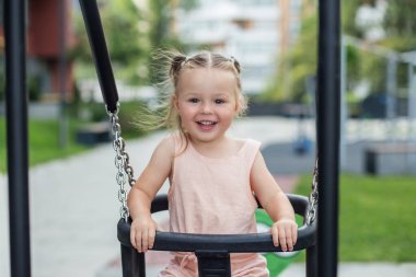 Gülücük saçı rüzgarda dalgalanan at kuyruklarıyla salıncakta güneşli bir günün tadını çıkarır..