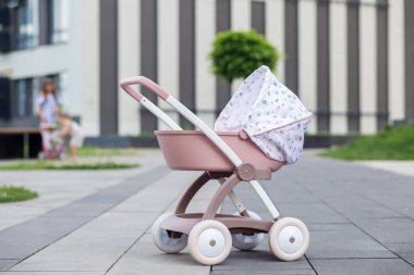 Ön planda, arka planda benzer oyuncaklarla oynayan bulanık çocukların oynadığı pembe oyuncak bebek arabası var..