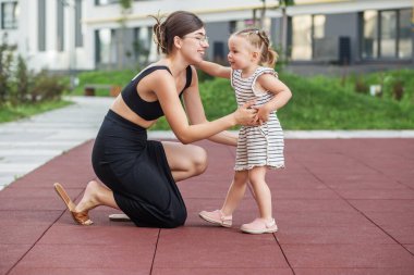 Anne, kızını dikkatle dinlemek için diz çöker. Gerçek anne-çocuk etkileşimi anı yaratır..