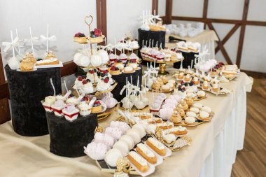 Varlıklı bir tatlı masası, içinde makaronlar, kekler ve meyveli şekerlemeler olan çeşitli tatlılar da var..