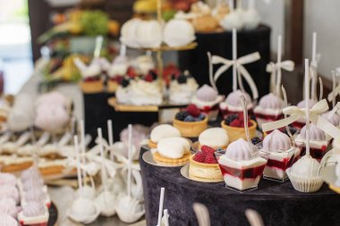 Varlıklı bir tatlı masası, içinde makaronlar, kekler ve meyveli şekerlemeler olan çeşitli tatlılar da var..