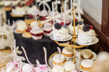 Varlıklı bir tatlı masası, içinde makaronlar, kekler ve meyveli şekerlemeler olan çeşitli tatlılar da var..