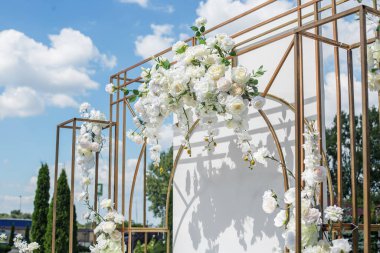 Modern metalik yapılar üzerinde beyaz güller ve orkideler sergilenen çarpıcı açık hava çiçekleri sofistike kutlamalar için.