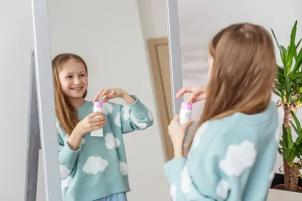 아름다움 루틴을 거울에서 그녀의 반사를보고있는 쾌활한 아이는 로션을 스톡 사진