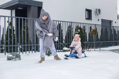 Karlı bir yerleşim bölgesinde, bir anne kışın, gülen çocuğunu kızağa çekerek, aile bağlarını güçlendirerek ve karda eğlenerek eğlenir..