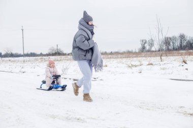 Karlı bir alanda, bir kadın kızakla yürümeye devam ederken sıcak koşu yapar. Kış günü birlikte açık havanın tadını çıkarırken sessiz bir zemin sunar..