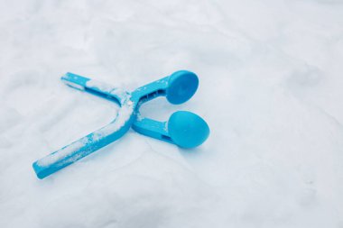 Parlak mavi bir kar küreği, huzurlu bir yerleşim bölgesindeki kışın kontrastını vurguluyor. Araç kısmen karla kaplı, yakın zamanda kullanıldığını gösteriyor.