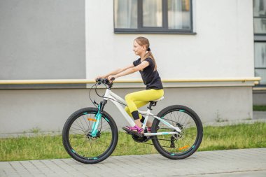 Genç bir kız kaldırımda bisiklet sürmekten hoşlanır, parlak renkli şık bir spor kıyafeti giyer. Bisiklet sürme yeteneğini sergileyerek neşeyle pedal çevirirken güneş batıyor..